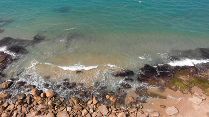 Top down view of Waves breaking on Empty Rocky beach Aerial