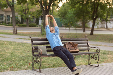 Portrait of handsome businessman relaxing on bench outdoors