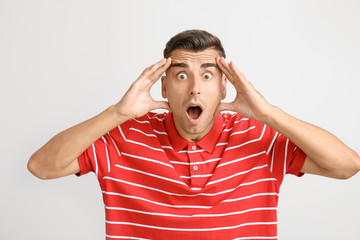 Shocked young man on light background