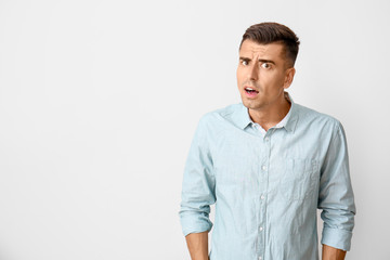 Fototapeta premium Suspicious young man on light background