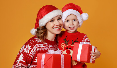 happy family mother and child son with christmas gifts on yellow background