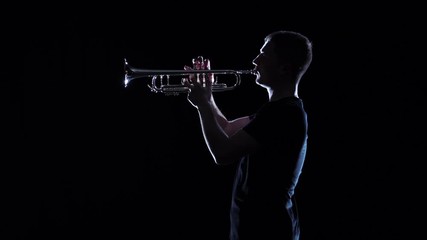 Man blows motif in wind instrument. Black studio, slow motion
