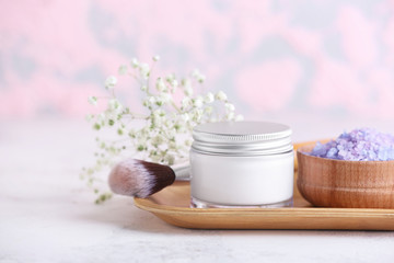 Fototapeta na wymiar Jar of cosmetics cream with sea salt and brush on table