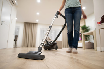 Wide angle photo of woman housewife or maid or service worker hoovering with vacuum cleaner in bright luxury appartment. - obrazy, fototapety, plakaty
