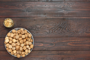 An organic walnuts in a metal tray and nutcreacker on a dark wooden table, copy space. Top view.