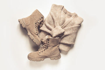 Female autumn winter cozy look  flat lying. Warm boots, sweater, bag on a light gray background. Concept of autumn fashion and trends.