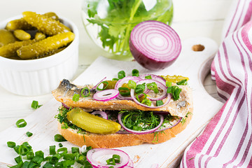 Traditional Dutch sandwich with herring and pickles cucumbers on white table. Smorrebrod.
