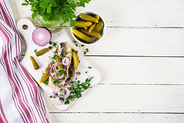 Traditional Dutch sandwich with herring and pickles cucumbers on white table. Smorrebrod.Top view