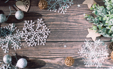 Christmas background of Christmas toys, spruce twigs,  snowflakes, stars, rattan balls and tinsel on a wooden brown table