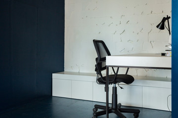 Loft style office with white brick walls and concrete columns. There is a meeting area with a large white table with black chairs