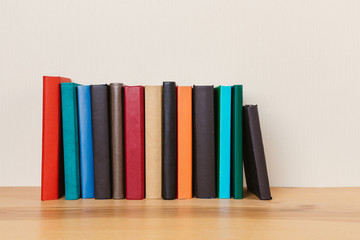 Simple composition of many hardback books, raw of books on wooden table and light  background