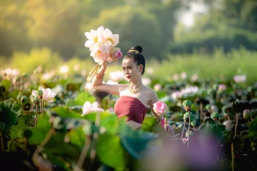 Abwaschbare Fototapete Asian woman collecting lotus flowers and she wear Traditional Thai dresses, Thailand © sunyawitphoto