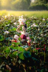 Naklejka na ściany i meble Asian woman collecting lotus flowers and she wear Traditional Thai dresses, Thailand