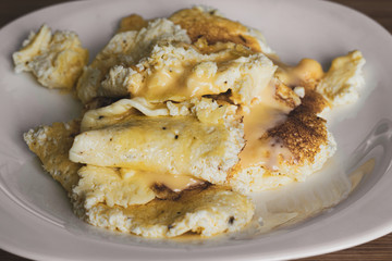 Tasty yellow chicken omelet with melted cheese on a white plate. Close-up