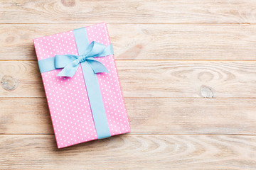 Beautiful gift box with a colored bow on the yellow wooden table. Top view banner with copy space for you design