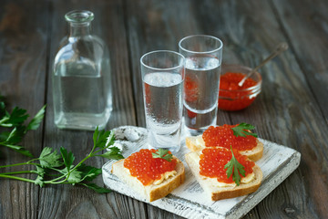 Vodka with salmon caviar and bread toast on wooden background. Alcohol pure craft drink and traditional snacks. Negative space. Celebrating food and delicious. Top view.