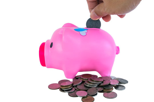 The hand of a man holding a coin drop put in a pink pig piggy bank on a white background, isolate.