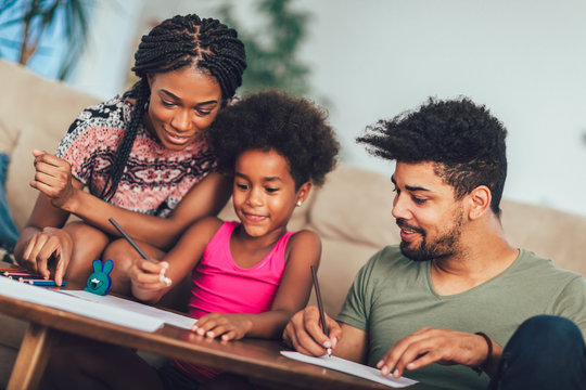 Mom And Dad Drawing With Their Daughter. African American Family Spending Time Together At Home.