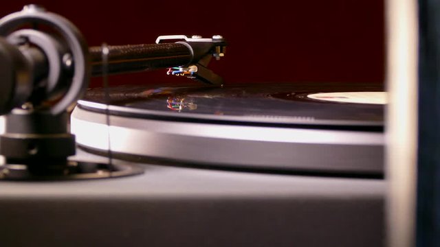 Close POV dolly shot past a hi-fi speaker to a traditional vinyl LP record playing on a turntable.