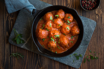 Homemade meatballs with tomato sauce and parsley in a frying pan