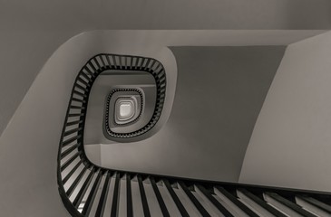 Gray scale low angle shot of a stairway going up surrounded by white walls