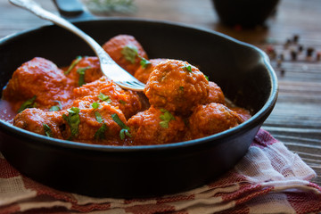 Homemade meatballs with tomato sauce and parsley in a frying pan - obrazy, fototapety, plakaty