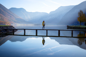 tourist girl in a hat and with a backpack stands on a wooden bridge