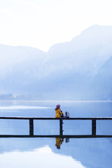 Naklejka premium tourist girl in a hat and with a backpack sitting on a wooden bridge