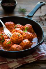 Homemade meatballs with tomato sauce and parsley in a frying pan