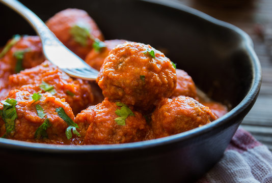 Homemade meatballs with tomato sauce and parsley in a frying pan