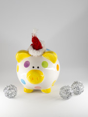 Colorful piggy bank with santa hat surrounded by silver ornaments isolated on white background