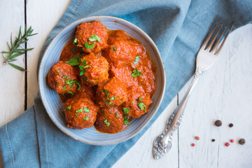 Homemade meatballs with tomato sauce and parsley in a bowl