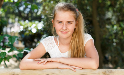 Teenage  girl standing near fence  in green park at summer day