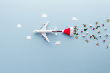 Christmas composition. Airplane flying in sky clouds fir star santa hat top view background with copy space for your text. Flat lay.