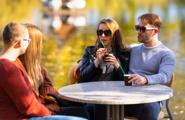 Two young couples enjoying coffee outdoors