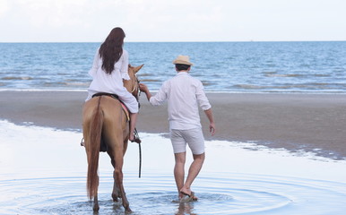 Couples are happily riding horses on the sandy beach