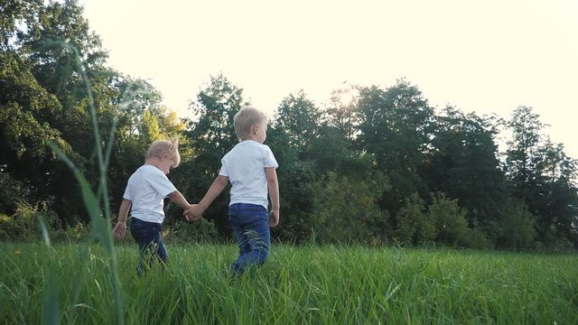 Happy family walking: funny slow motion video little kid boy hold hands go nature play whirl a and girl brother and sister hold hand on nature happy children concept. children happy family boy girl
