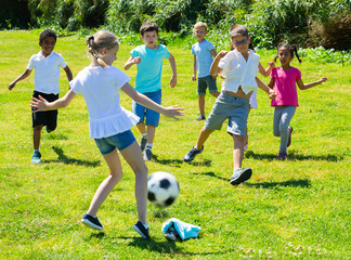 Group of kids are running and playing football in the park