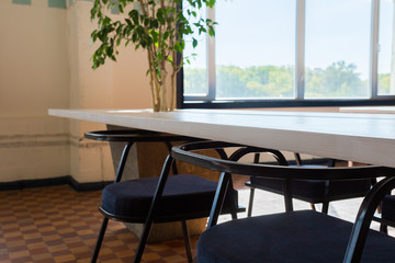 Loft style office with white brick walls and concrete columns. There is a meeting area with a large white table with black chairs