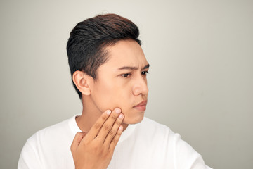 Portrait of shirtless young handsome Asian man checking his face for skin care and beauty concepts...