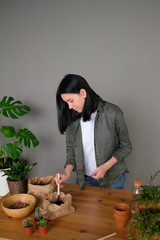 Young woman caring for potted indoor plants.