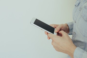 Image of a young woman working on a mobile phone at home on a background of light wall