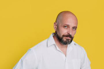 Handsome middle-aged man on yellow background looking at camera.  with copy space