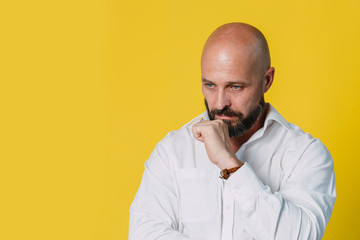 Handsome serious middle aged man meditate on yellow background with copy space.