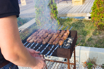 A man fries meat on the grill. Weekends