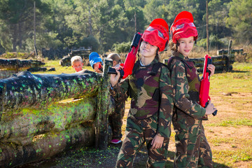  two girls paintball players with marker guns ready for game