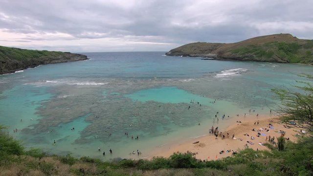 Panoramic view of Hanauma Bay of Oahu Island  from the Lookout on a cloudy day; view includes the Toilet Bowl, Pai Olu Olu Point, coral, beach and tourists