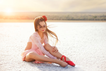 girl ballerina dancer in a pink dress on a snow-white salty dried lake. Fantastic landscape and a girl in red punata and a pink dress.