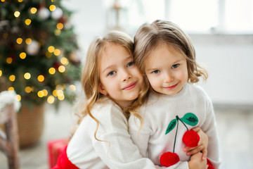 Two little sisters near the Christmas tree.