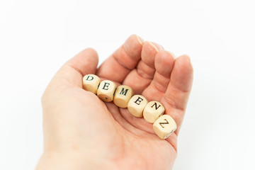 Hand with letter cubes and the german word for dementia, white background